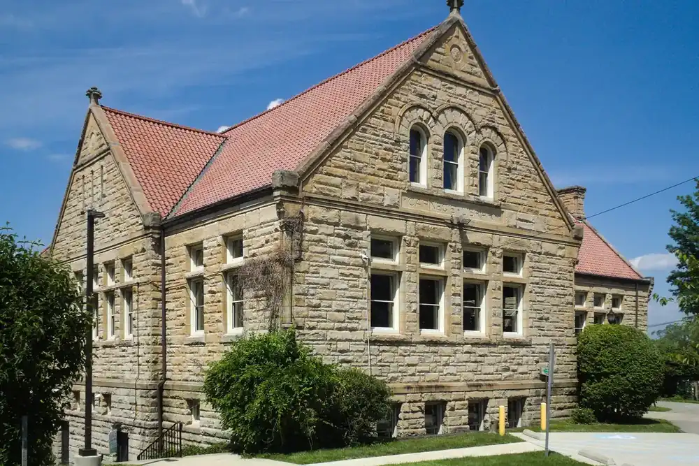 Stone Carnegie Free Library building with a red tile roof and arched windows in McKeesport, Pennsylvania