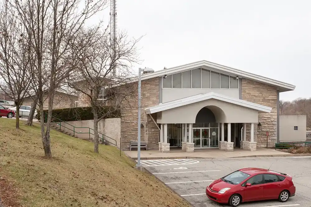 Stone and stucco Whitehall Borough municipal building with a columned entrance and parking lot
